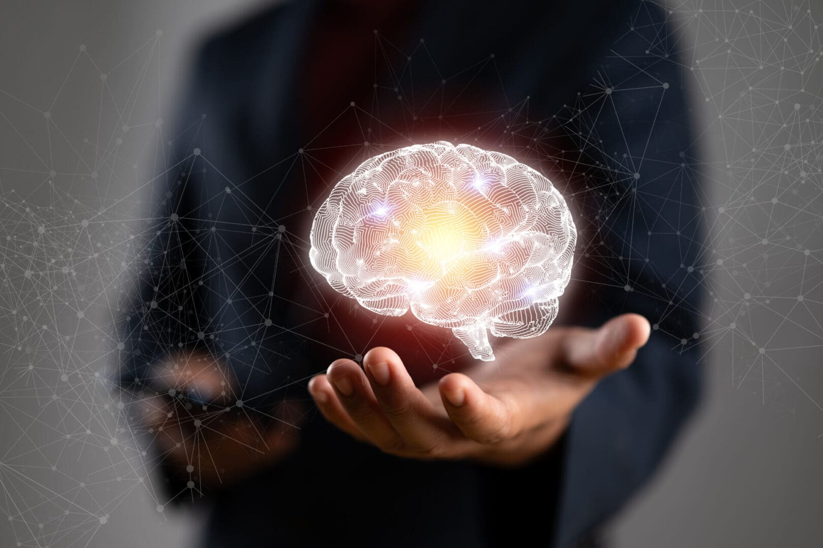 A glowing digital brain floating above a person's hand.